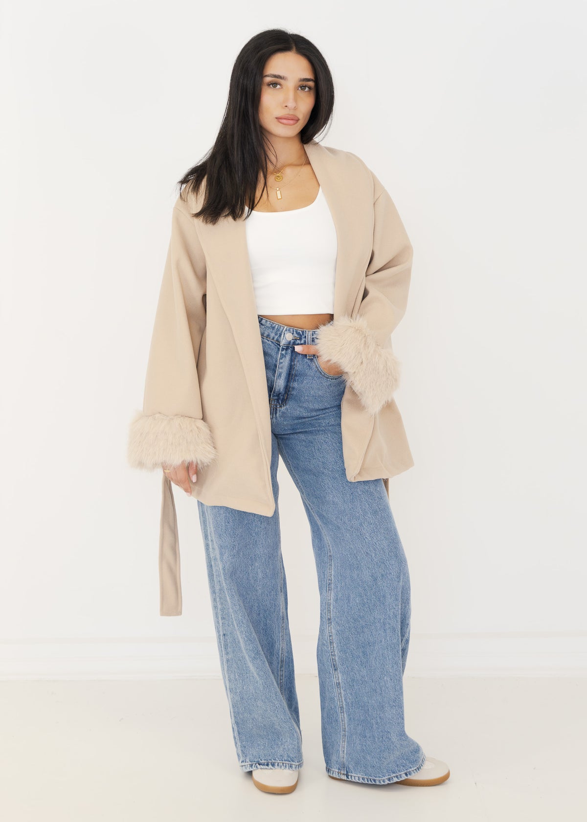 Offen getragener beiger Kurzmantel mit Schalkragen über weißem Crop-Top und Jeans