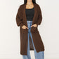 Lange Damen-Strickjacke in Braun offen getragen über schwarzem Top und Wide-Leg-Jeans