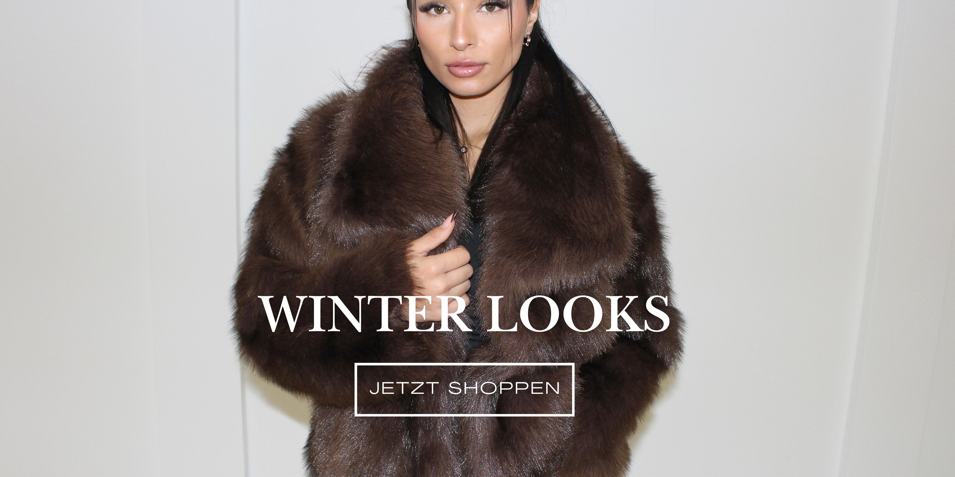 Modell trägt eine braune Kunstfelljacke als Winter Look vor hellem Hintergrund
