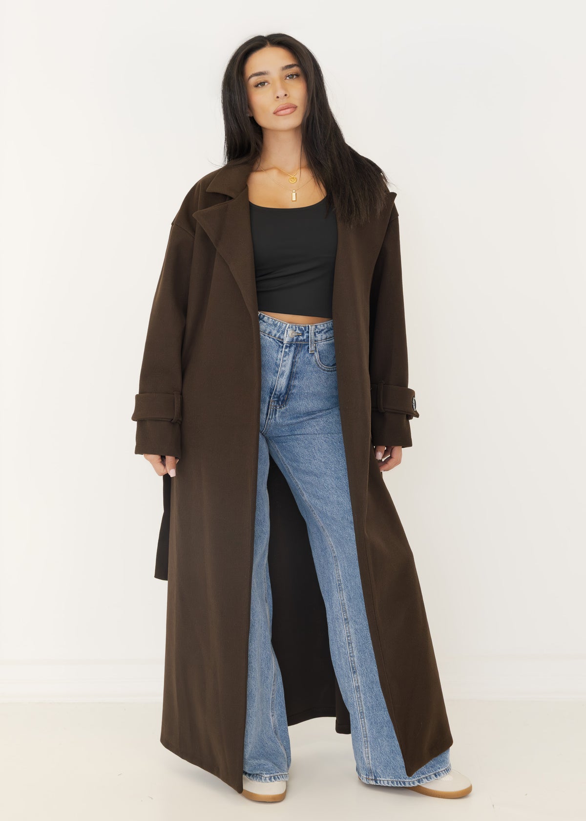 Offen getragener Oversize-Mantel in Dunkelbraun über schwarzem Top und blauer Wide-Leg-Jeans