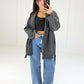 Frau in anthrazitfarbener Wickeljacke mit Bindegürtel zu Wide-Leg-Jeans, Vorderansicht