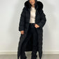Modell trägt einen langen Damen Steppmantel mit Kapuze und Taillengürtel – NAHA Wintermode