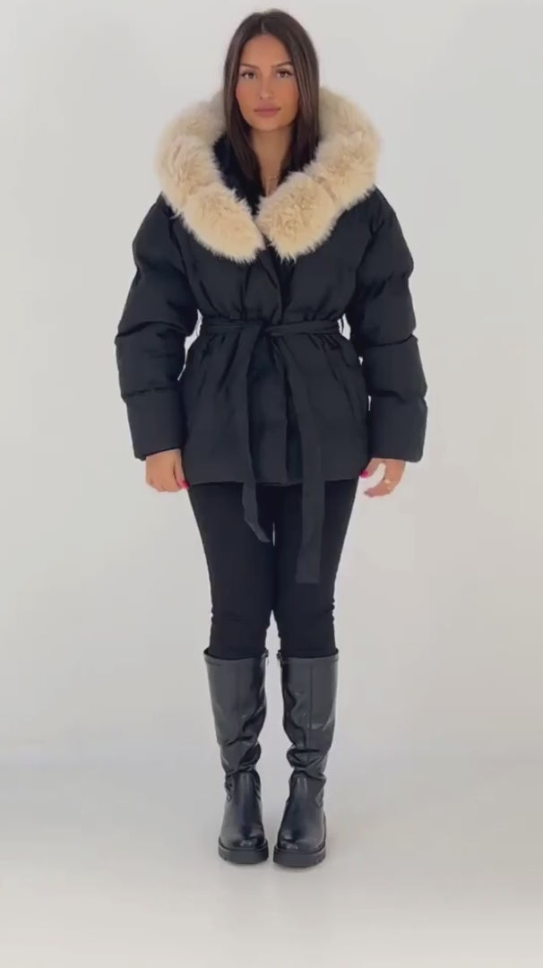 Schwarze Damen Steppjacke mit cremefarbener Fellkapuze und Bindegürtel, getragen mit schwarzen Stiefeln – NAHA