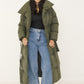 Khaki Puffer Mantel offen getragen zu schwarzem Top und Wide-Leg-Jeans