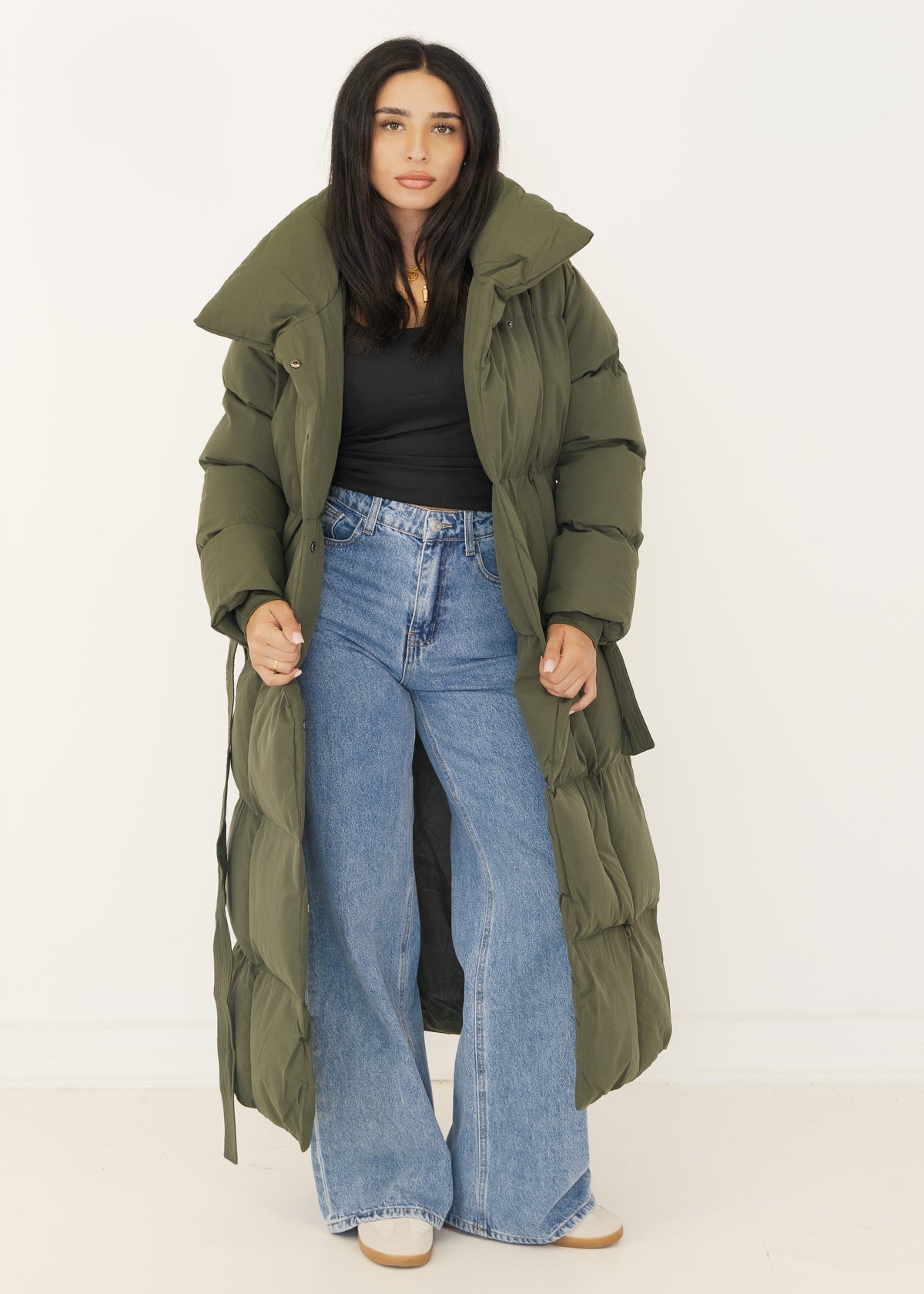Khaki Puffer Mantel offen getragen zu schwarzem Top und Wide-Leg-Jeans