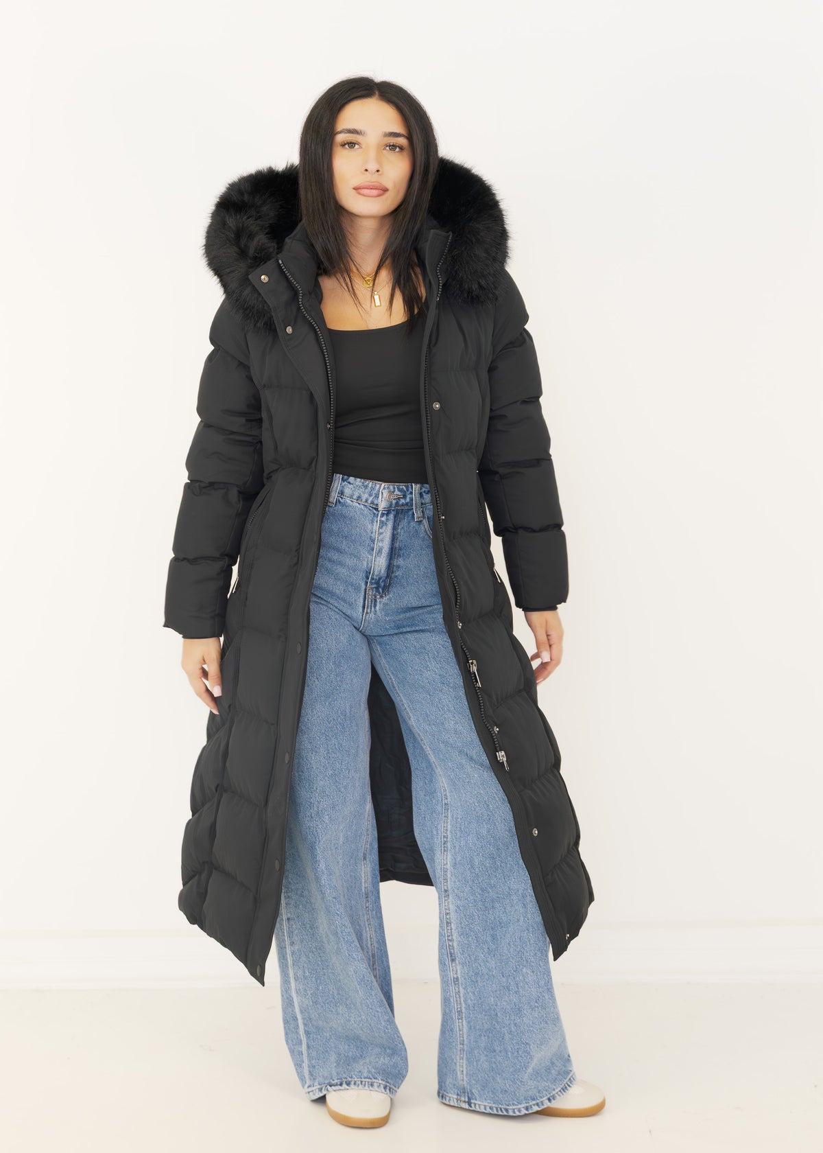 Schwarzer Steppmantel offen getragen zu schwarzem Top und Wide-Leg-Jeans