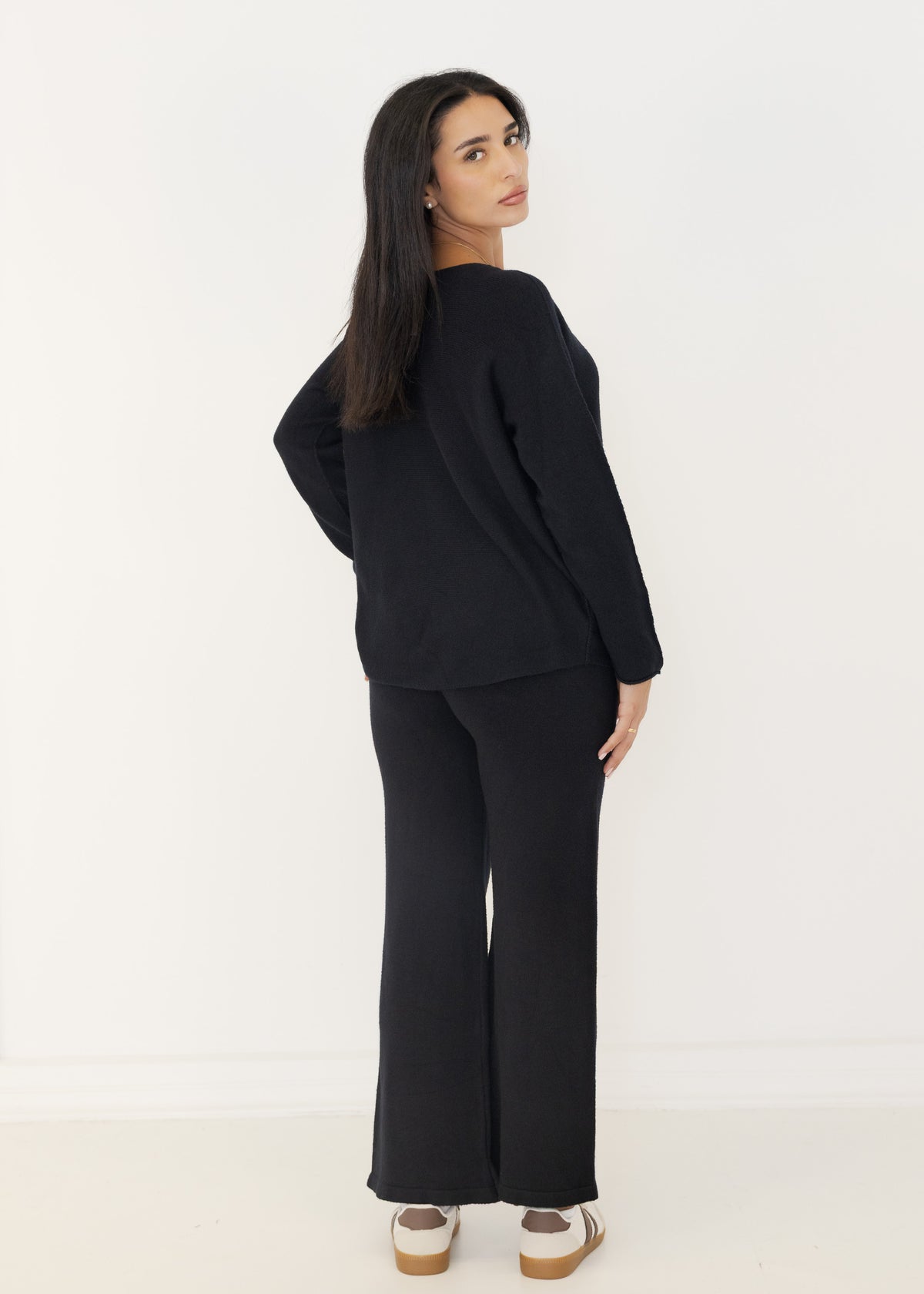 Rückansicht des schwarzen Strick-Sets mit lockerem Pullover und gerader Strickhose