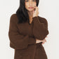 Nahaufnahme der braunen Strickjacke mit Ballonärmeln, Rippbündchen und Tasche