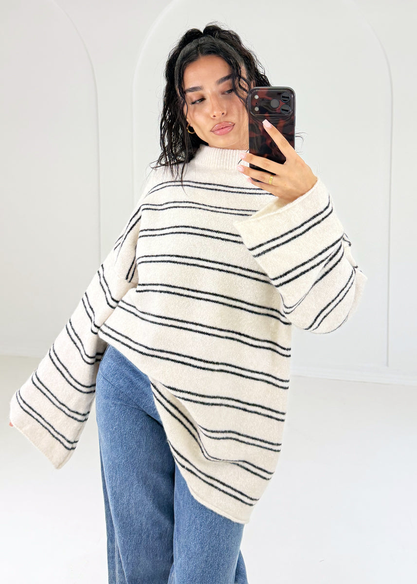 Seitliche Ansicht: Ringelpullover in Creme mit weiten Ärmeln und schwarzen Streifen