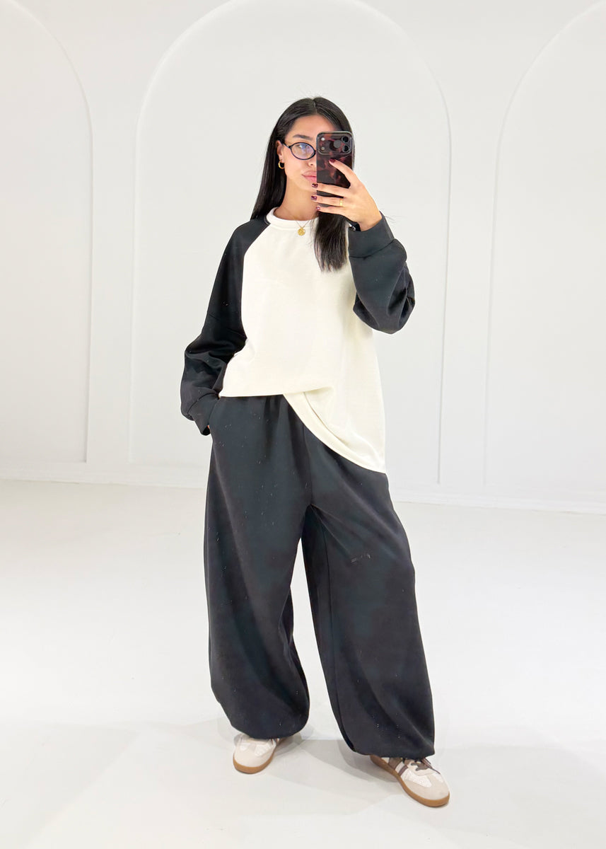 Oversize-Sweat-Set in Creme und Schwarz mit Hand in der Hosentasche