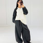 Frau in Oversize-Sweat-Set mit Raglan-Sweatshirt in Creme-Schwarz und weiter schwarzer Ballonhose, ganze Figur