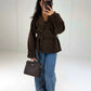 Frau in kurzer schokobrauner Trenchjacke mit Gürtel zu Wide-Leg-Jeans, Vorderansicht