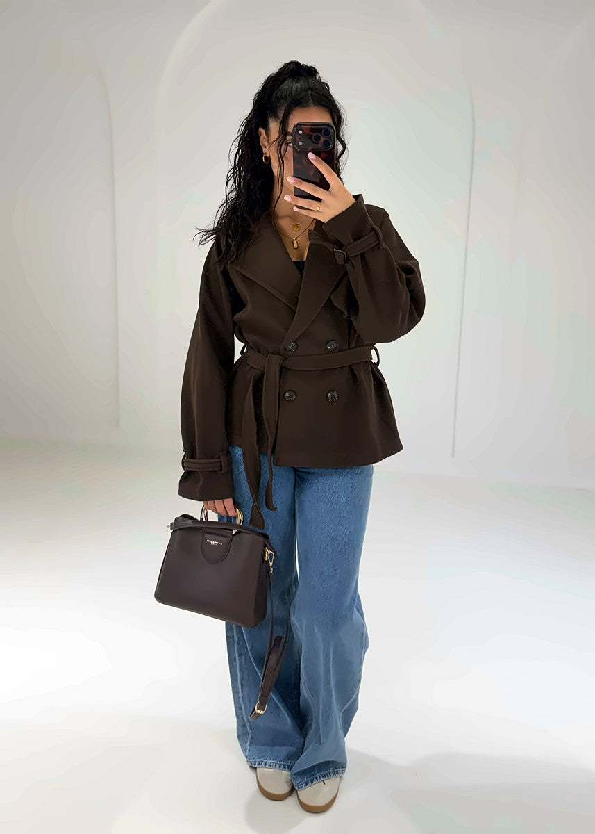 Frau in kurzer schokobrauner Trenchjacke mit Gürtel zu Wide-Leg-Jeans, Vorderansicht