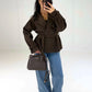 Model in brauner Zweireiher-Jacke mit Gürtel, Hand an der Hüfte