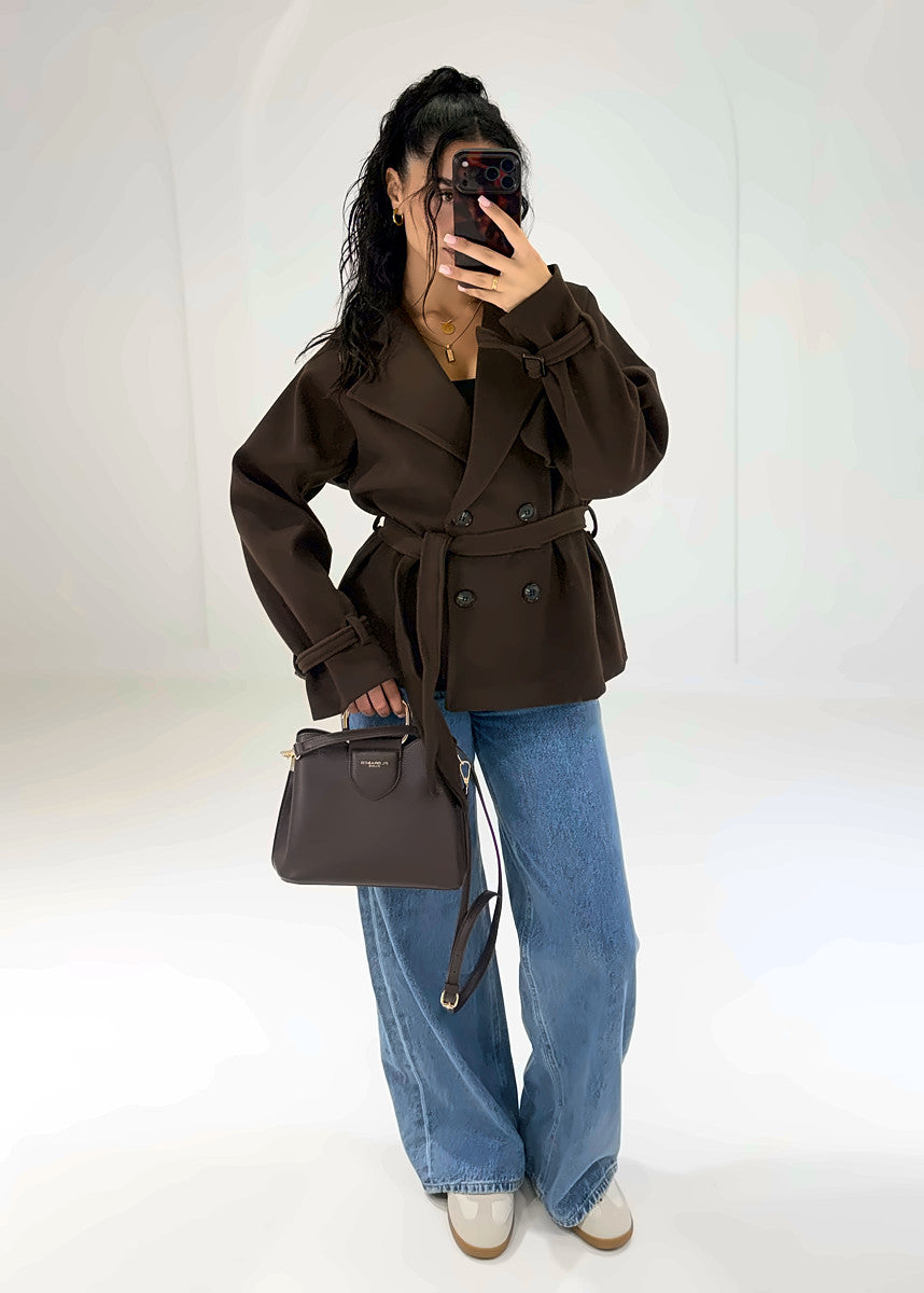 Model in brauner Zweireiher-Jacke mit Gürtel, Hand an der Hüfte