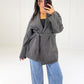 Frau in anthrazitfarbener Wickeljacke mit Bindegürtel zu Wide-Leg-Jeans, Vorderansicht