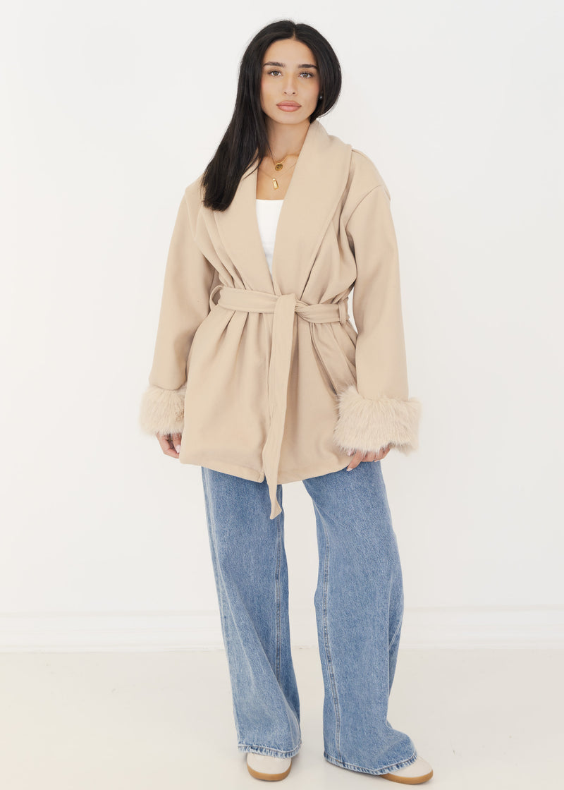 Damen Wickeljacke in Beige mit Bindegürtel und Kunstfell-Manschetten, getragen zu heller Wide-Leg-Jeans