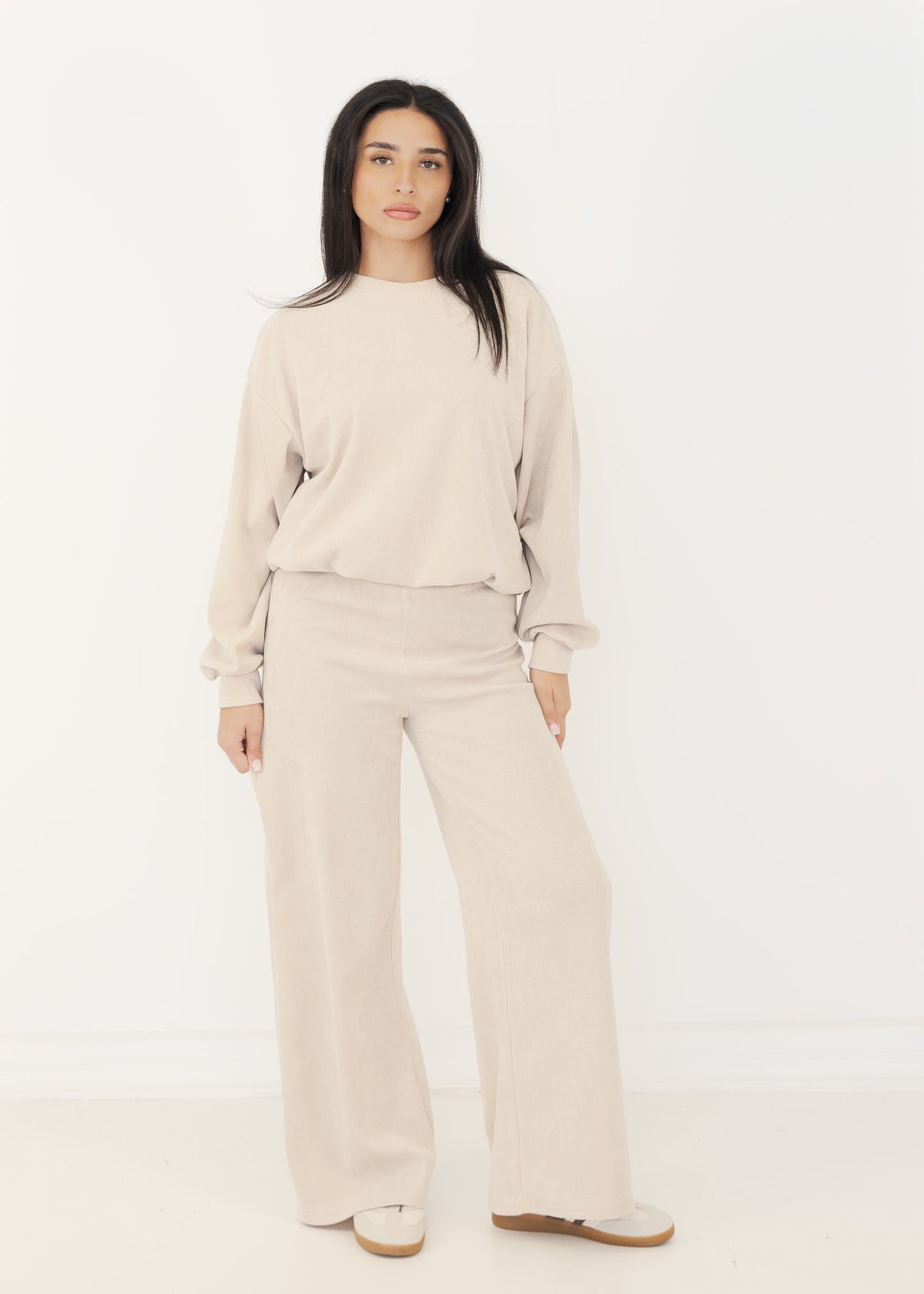 Damen Strick-Zweiteiler in Beige aus Pullover und weiter Strickhose, getragen mit Sneakern