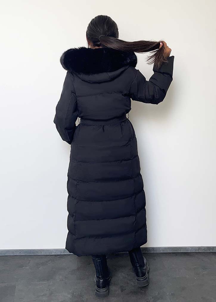 Modell trägt einen langen Damen Steppmantel mit Kapuze und Taillengürtel – NAHA Wintermode